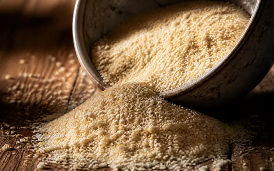 Macro detail of coarse Brazilian cassava meal spilling from a handmade ceramic bowl